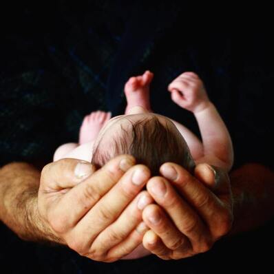Newborn baby held in father's hands